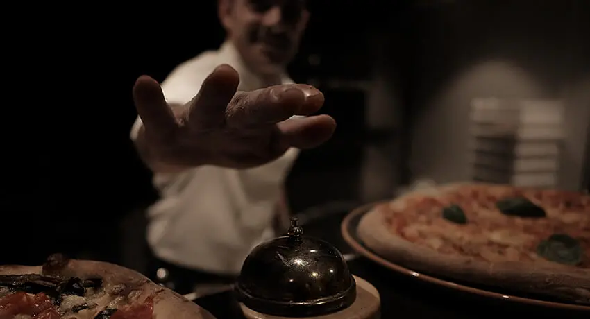 Kock på World of Riccardos i Halmstad plingar på klocka för att berätta att pizzor är färdiga för servering.