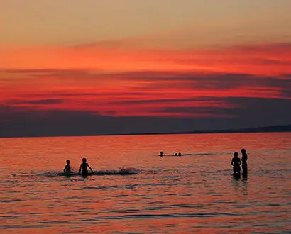 Menschen baden bei Sonnenuntergang